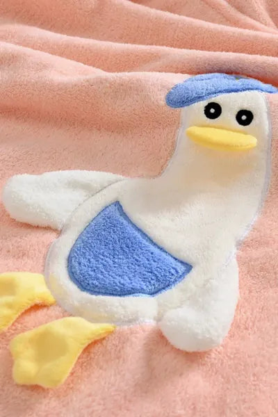 A close-up of a soft, pink towel with a white and blue duck applique.