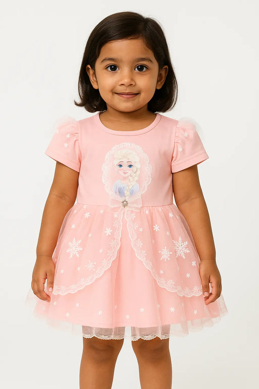 A young girl with short dark hair smiles, wearing a short-sleeved white top with a subtle floral print and a rounded collar underneath an olive green overall dress. The dress has a cream-colored bib pocket with embroidered pink cherries. This is a charming piece of girls kids clothing and trending clothes for girls, showcasing a sweet style in girls fashion. It's a lovely dress for kids girls.