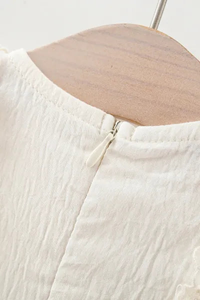 Girls fashion trends: A delicate white dress with a miniature bag, a beautiful example of girls kids clothing.
