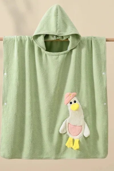 A soft, hooded green towel with a white and blue cartoon duck applique hanging from a wooden rod