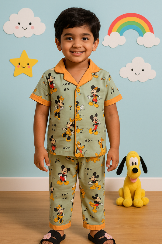 Cosy Boys Nightwear Collection - Kids sleepwear featuring a pants set with a playful design of popular cartoon characters. The boy is wearing green pyjamas with orange trim, decorated with images of Mickey Mouse and friends. The background includes cheerful elements like a rainbow, clouds, and stars