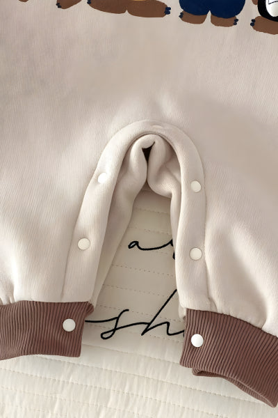 Close-up of a beige garment with brown accents and white buttons on a light background.