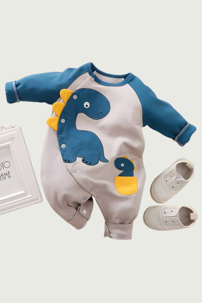 Baby romper with dinosaur design and baby shoes on a light gray background