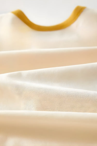 Close-up of beige fabric with a yellow trim on a light background