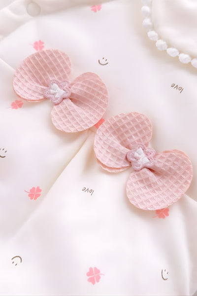 Pink butterfly decorations on a white fabric background with floral patterns.