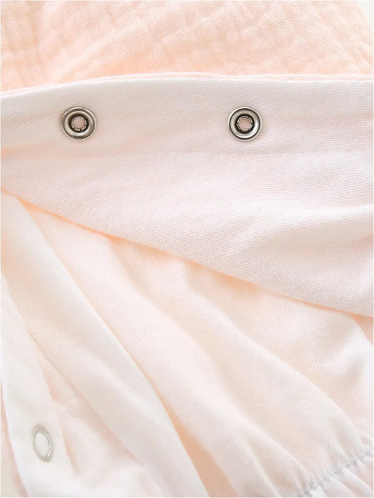 A close-up view of the snap closures on a light-colored romper.
