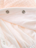 A close-up view of the snap closures on a light-colored romper.