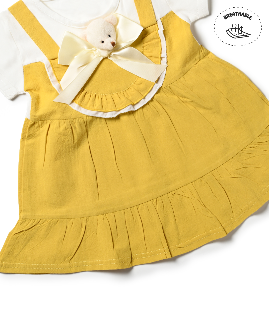 A stylish outfit from girls kids clothing: a yellow dress with a white top and teddy bear accent